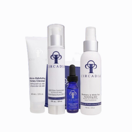 Essential Regimen Bundle Travel Kit with skincare products including cleanser, sunscreen, serum, and hydrating milk.